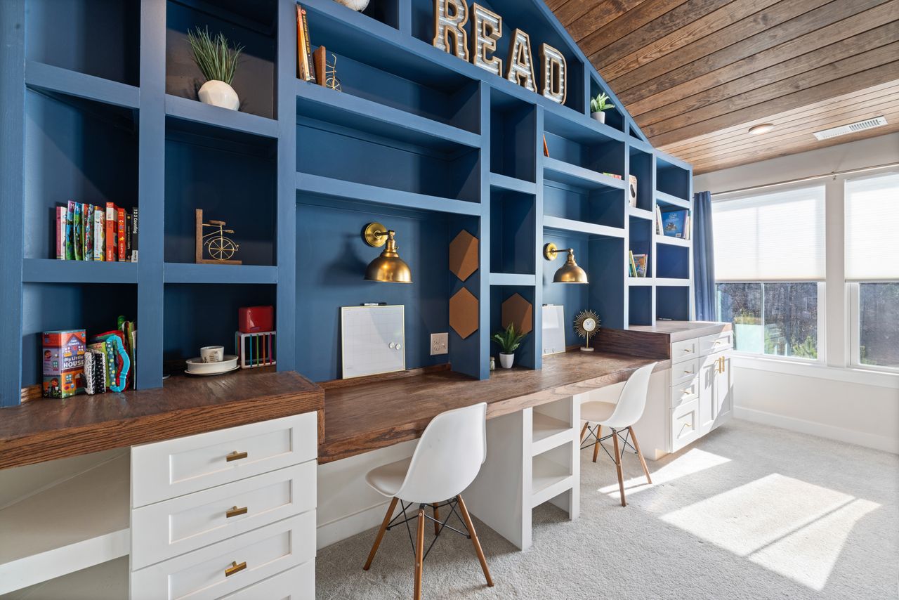 services-01 Bright home study room with custom blue bookshelves, wooden desk, and white chairs.