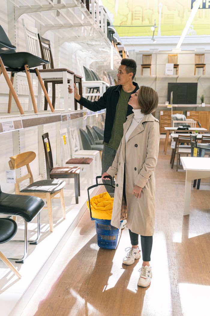 who-we-are A couple browsing a selection of chairs in a well-lit modern furniture store.